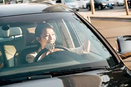城市,阳光开车打招呼的青年女人背景