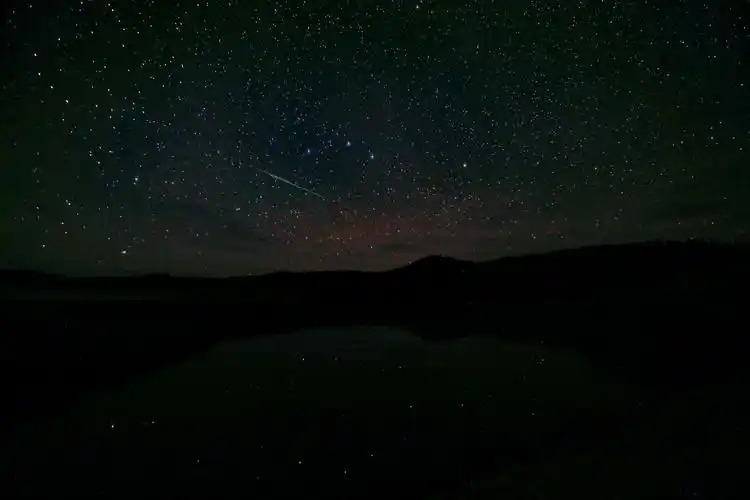 这张照片很有意思,天空中可以看到一颗流星略过,水面上有星空的倒影