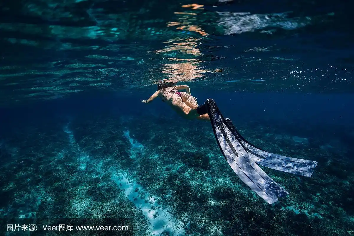 女自由潜水者与鳍滑过珊瑚礁.