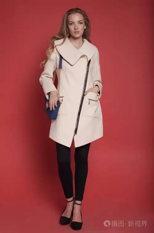 美丽的年轻女子,穿着外套红色背景上摆姿势