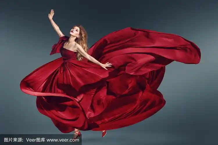 穿着飘动的红色连衣裙跳舞的时尚女子