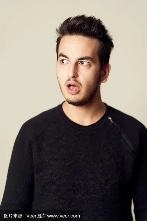 一个年轻的男性成年人的大头照,在工作室里穿着休闲服,干净的纯色背景