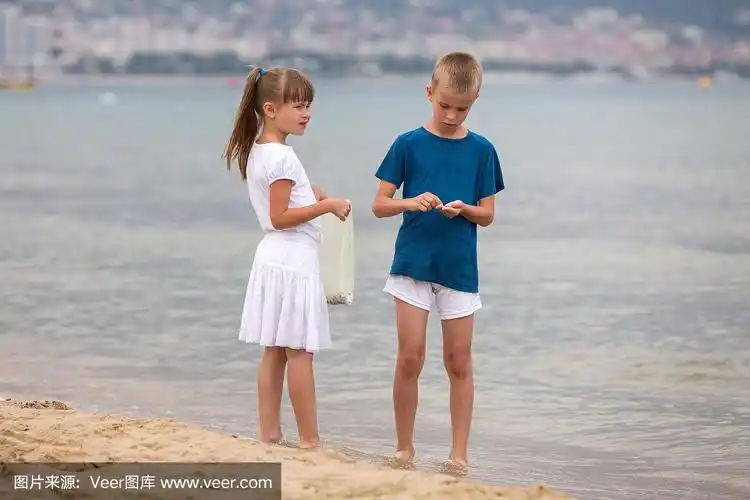 夏天,两个男孩和女孩赤脚走在海边的水里.