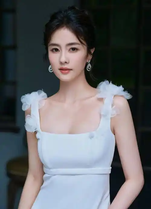 金晨身穿白色深v连衣纱裙,脖子戴着大珠宝项链,她坐在椅子上靓丽多姿