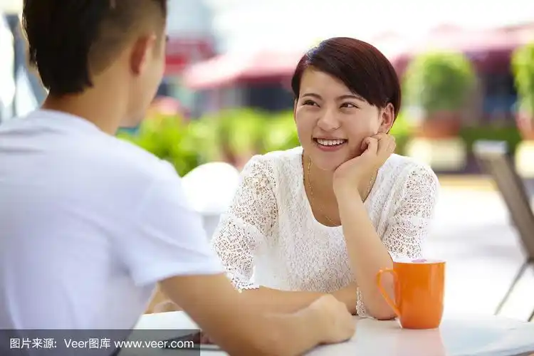 快乐的年轻女子与朋友在咖啡馆交谈