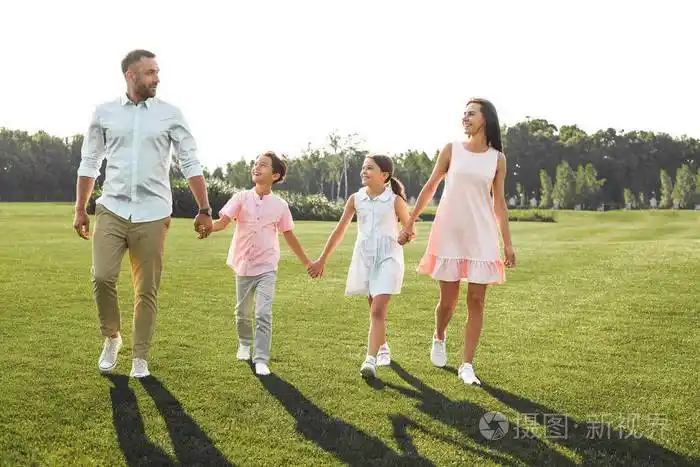 我爱我家整整一家四口幸福而年轻手牵着手微笑着走在户外