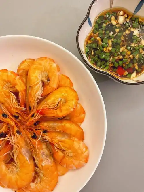白灼虾做法:1.锅内铺葱段姜片,再放上虾2.