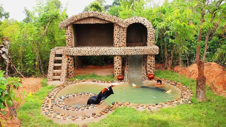 房子外墙贴鹅卵石!现在又在房子门前建游泳池和滑梯!太有才了!