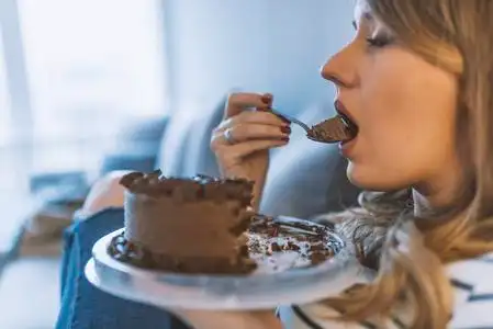 漂亮的女孩喜欢吃巧克力蛋糕.漂亮的年轻女人吃一个甜蛋糕.