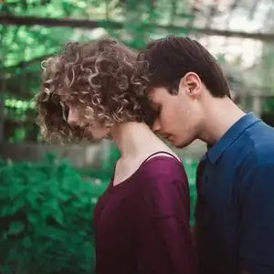 英俊的贵族男人温柔地亲吻苍白女人的脖子.片刻的柔情.绿叶背景照片