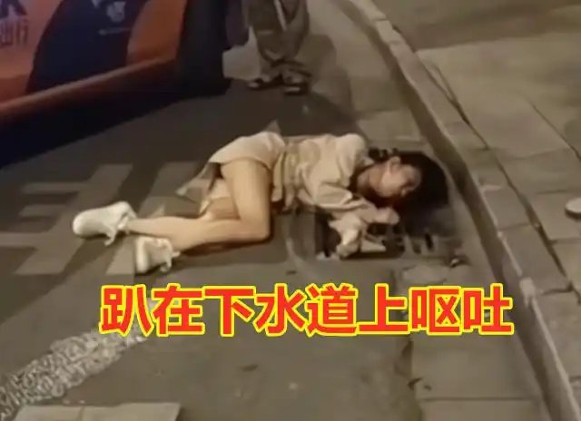女子醉酒后趴在下水道呕吐,因难受不停扭动身躯,酒友不知去哪了