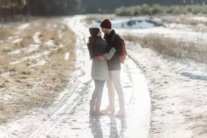 年轻的时髦夫妇在冬季公园中拥抱彼此