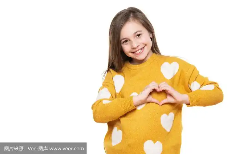 一个小女孩的工作室肖像在白色的背景做一个心的手势与她的手.