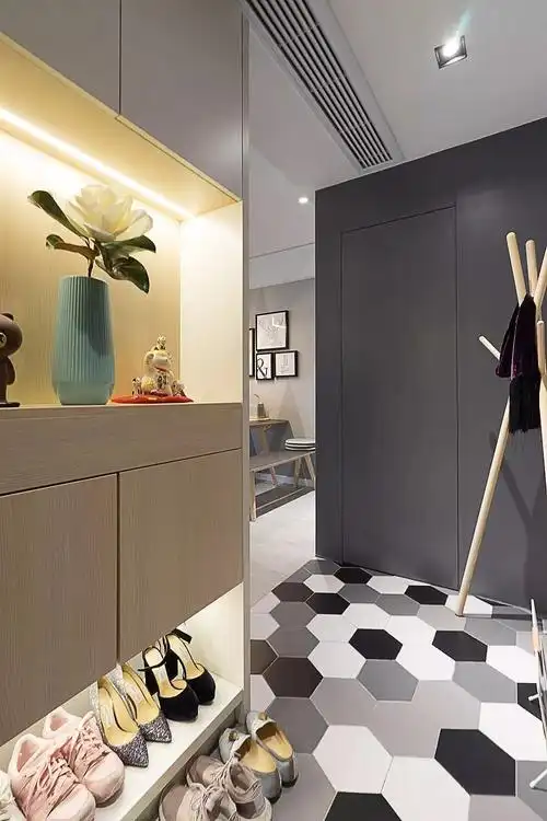 入户的玄关空间,一侧是做了嵌入式的到顶鞋柜,鞋柜的底部和中间都留空