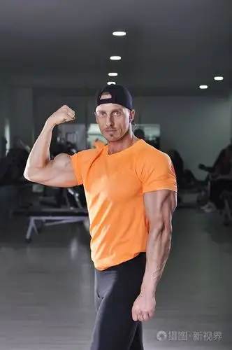 帅强大健壮的男人在健身房里摆姿势.与完美手臂肌肉的强健美