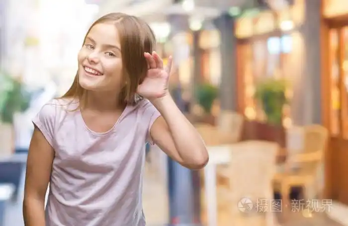 年轻美丽的女孩在孤立的背景下微笑着用手在耳朵听谣言或八卦.