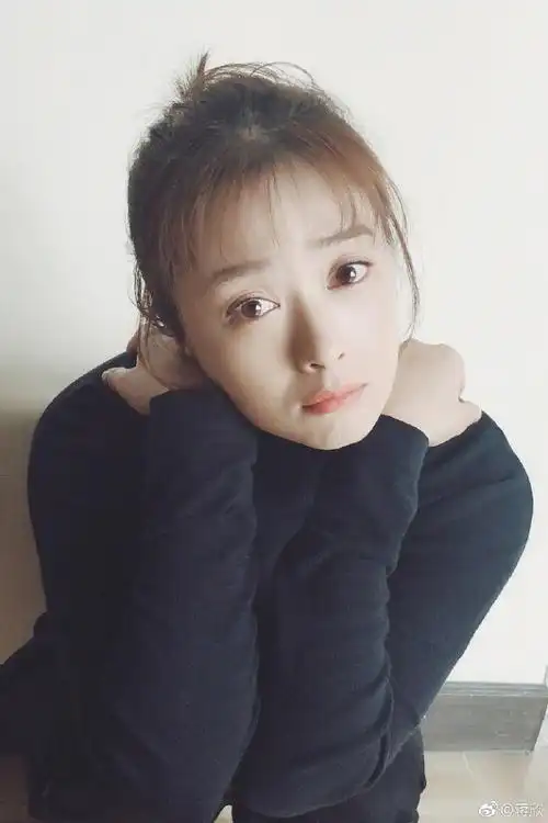 组图蒋欣穿黑衣盘发气质温柔双手捧脸蹲地露甜笑很俏皮照片中蒋欣穿着