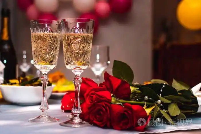 喜庆的酒杯上摆着闪闪发光的香槟新婚夫妇桌上摆着一束红玫瑰选择性