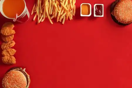 肉汉堡,薯条和饮料在红色背景上的玻璃.外卖的组成照片