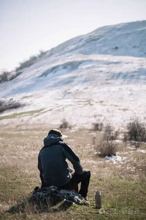 一个人坐在雪山上的岩石上