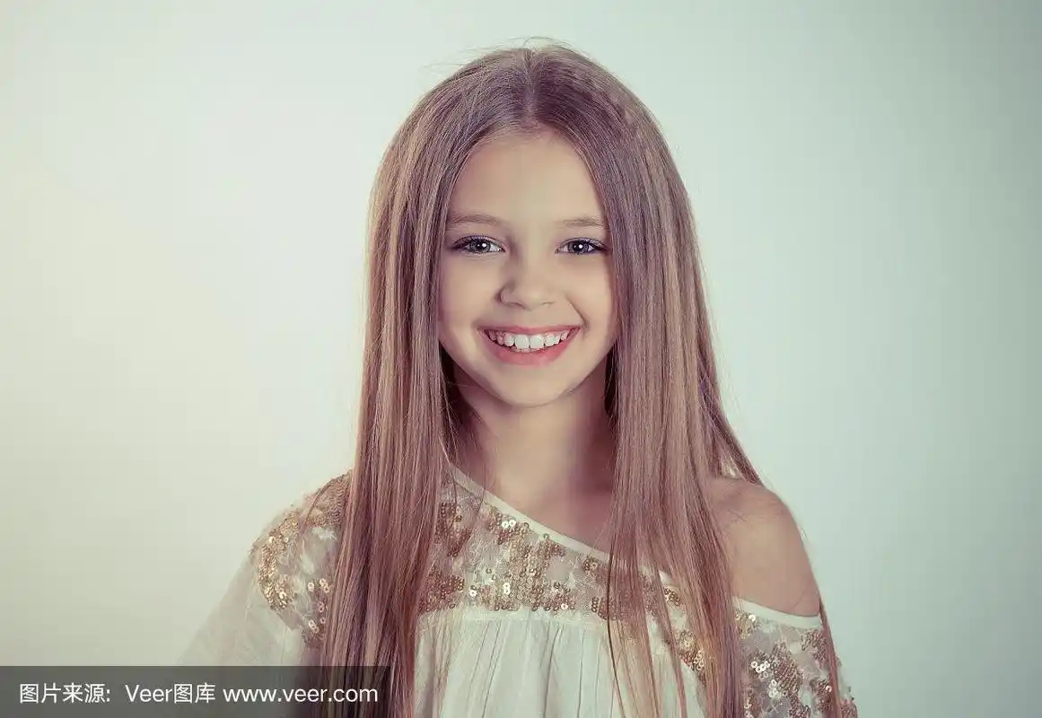 金发小美丽的阳光女孩微笑着看着你的相机在绿色的背景