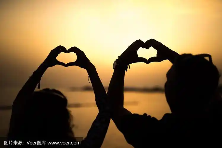 晚霞上一对成熟的夫妇用手做心形的剪影.
