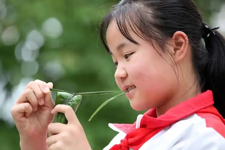 2021年6月11日,贵州省黔西市洪水镇平桥小学,学生包粽子.