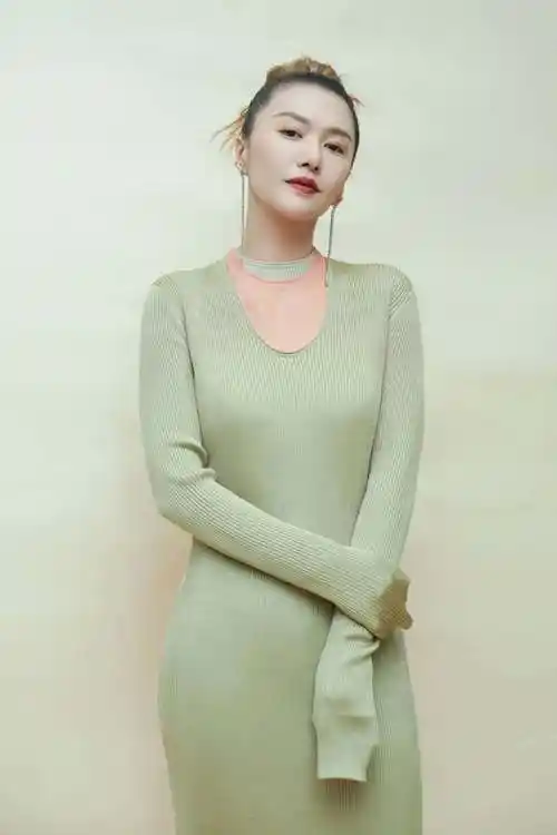 绿色针织长衫简洁大方的低胸圆领,展现修长的颈部,谭维维高高扎起头发