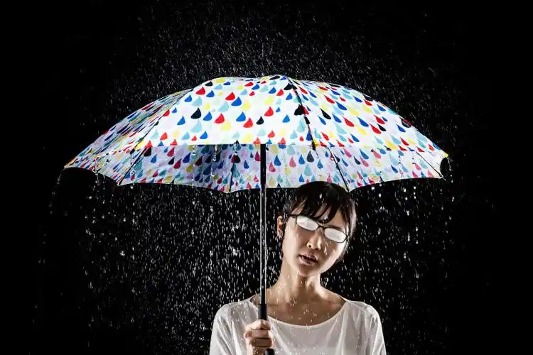 黑背景下雨天打雨伞的女性