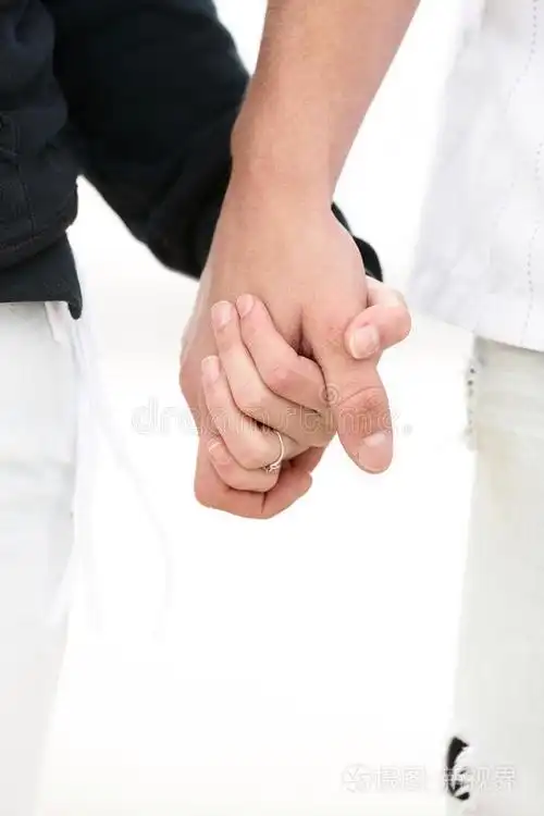 海滩上的一对年轻夫妇双手合十照片-正版商用图片0j72y8-摄图新视界