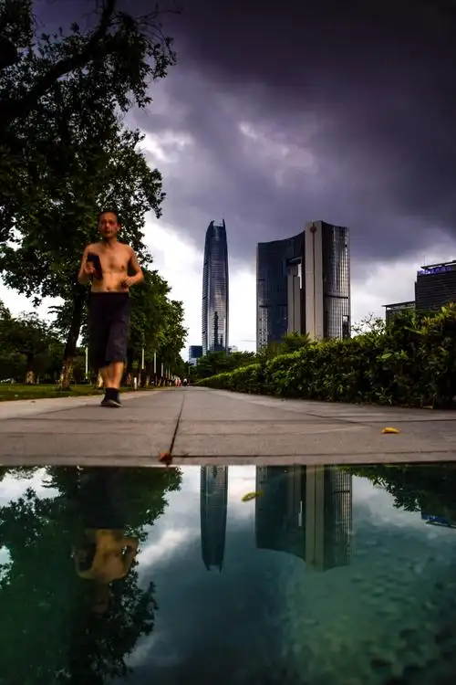 在一个乌云密布的傍晚,一个大叔光着膀子悠闲地在绿道跑着步,天气并不