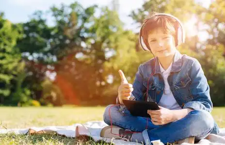 有吸引力积极的儿童在野餐时使用他的平板电脑照片