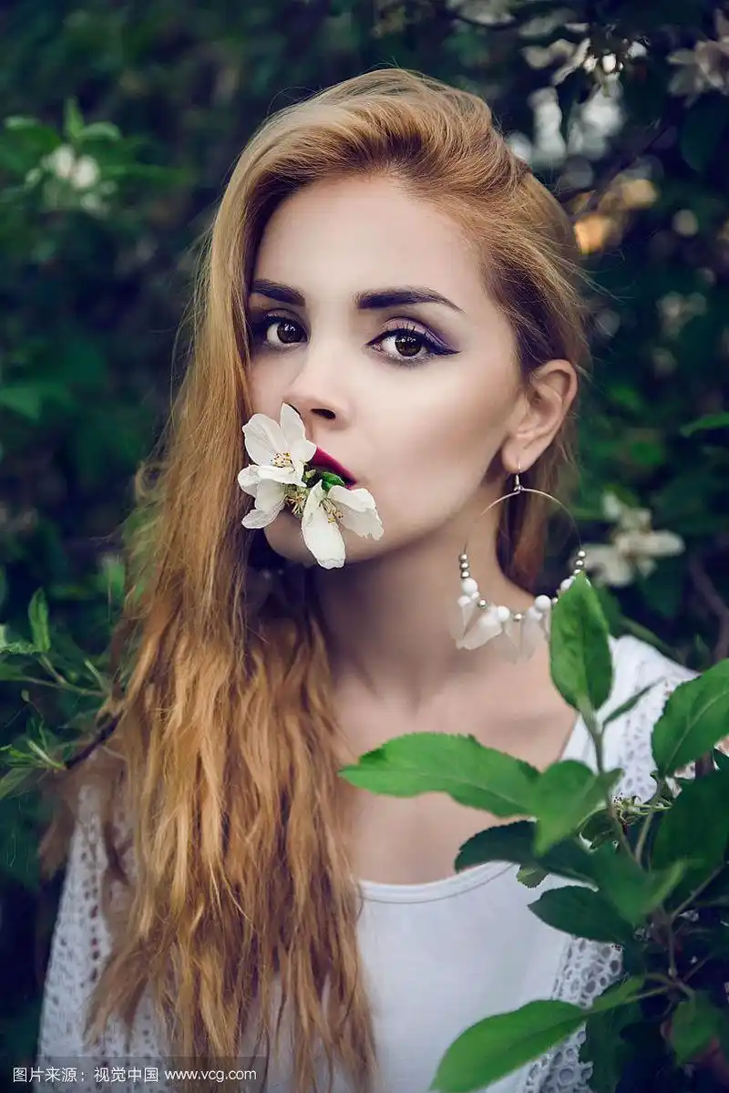 漂亮的金发女人嘴里叼着花