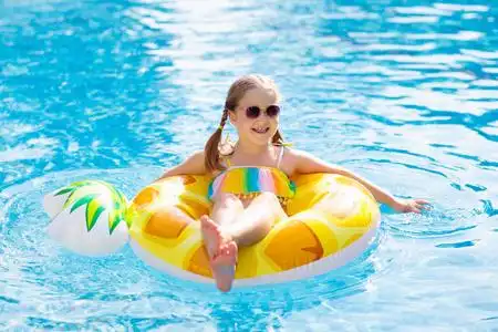 儿童戒指带充气菠萝玩具戒指的孩子漂浮在游泳池里.
