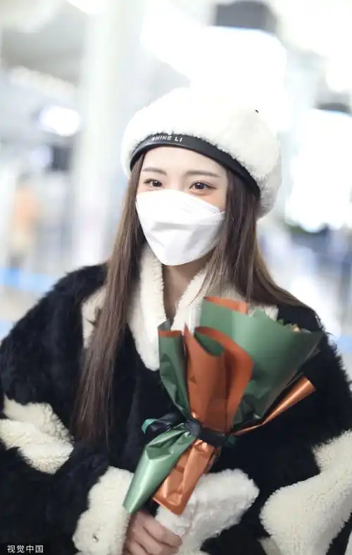 组图:郑乃馨戴白色贝雷帽现身机场 手捧粉丝赠送花束笑眼弯弯