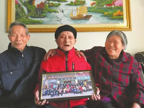 手捧去年生日拍的全家福,如今五世同堂的白美全(中)和儿子儿媳笑得很