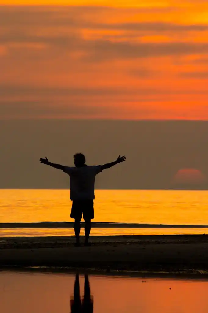 海滩上的男人,在日落海滩上的人的剪影.