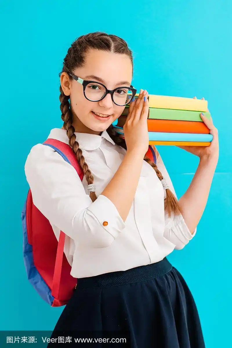 一个戴眼镜的女学生的肖像与课本在黄蓝色的背景在工作室.