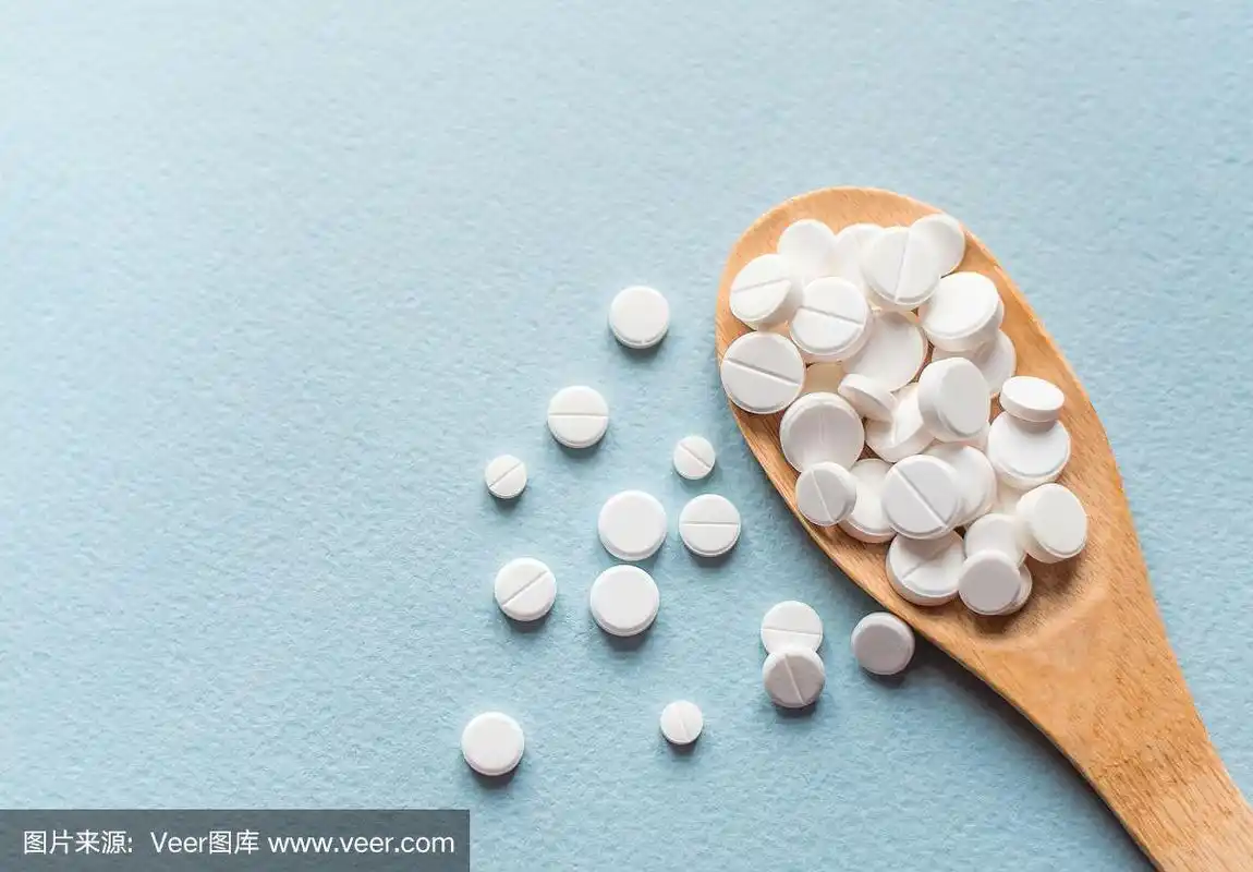 特写白色药片,药片放在木勺里放在蓝色的桌子上.医学健康理念.制药学.