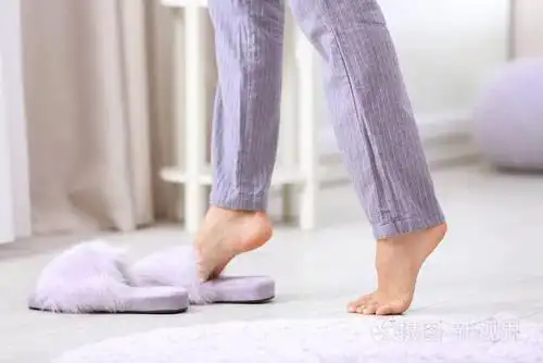 女人赤脚走在家里的空间里发短信. 地板供暖