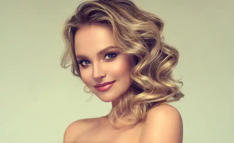 漂亮的金发模特,卷曲,宽松的发型和迷人的妆容.色彩,魅力.