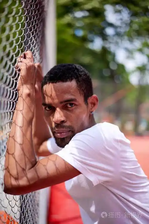 手举铁丝网围栏的黑人篮球运动员