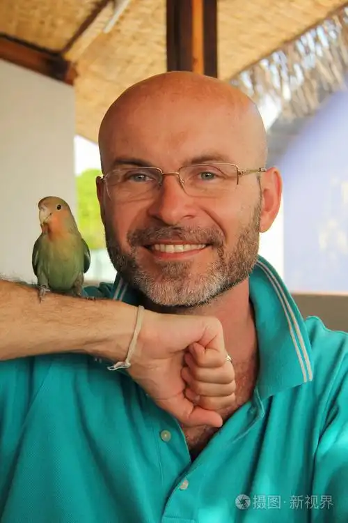 微笑着一只鹦鹉他手上的胡子的光头男人