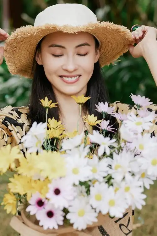 张柏芝身穿着碎花衬衫,头戴草帽,手捧黄白雏菊花束