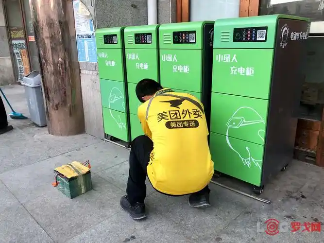 一位美团外卖骑手在使用"小绿人"的充电柜(图源:王艺瑾/36氪)
