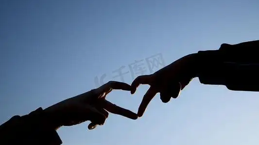 比心手势摄影照片_情侣蓝天下比爱心手势剪影