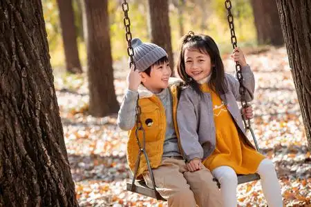 秋天户外小男孩和小女孩一起荡秋千