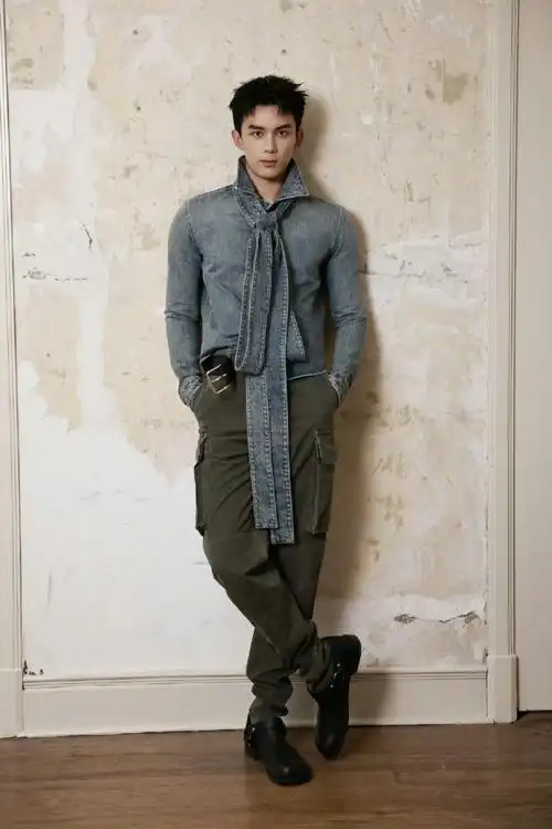 他身穿loewe 2024秋冬男装系列,巨大的蝴蝶结装饰牛仔上衣搭配军绿色