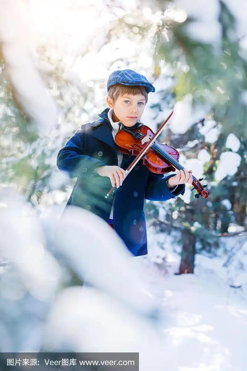 冬天的童话.可爱的男孩小提琴手在冬天的森林