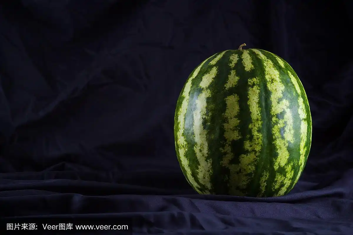黑布上的西瓜.黑色背景下的整个西瓜.素食主义者的健康食品.本空间